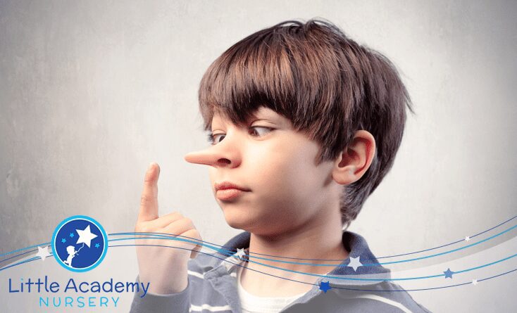 A child is pointing his right hand's finger towards his nose