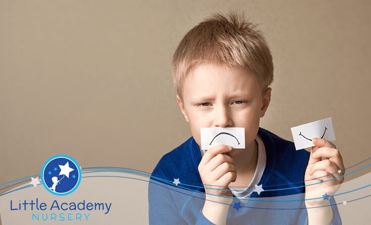 A child holding piece of paper in his hands and its denoting the sad face over the paper.
