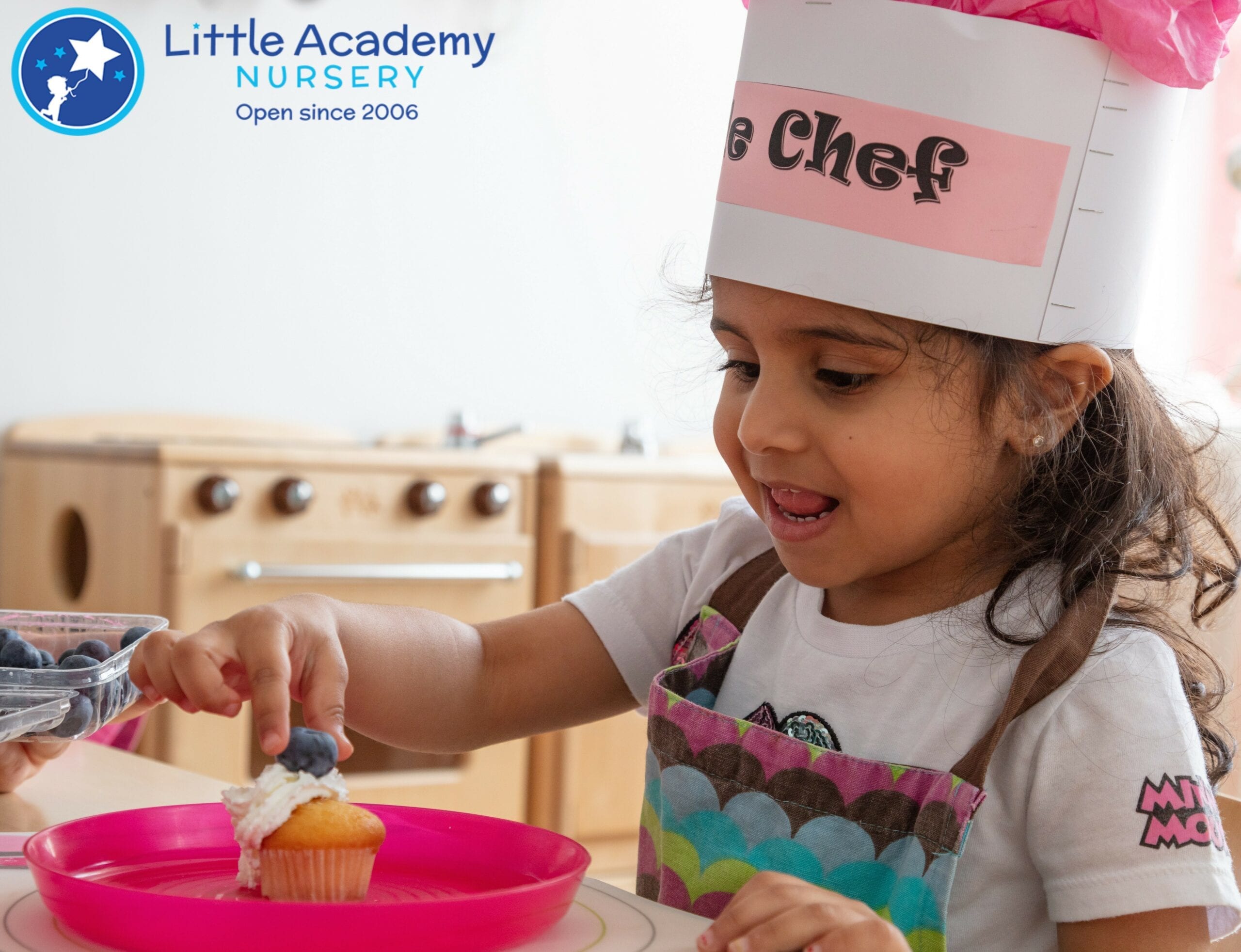 A Girl wearing a cooking hat on her head and picking up a piece of cake in her right hand.